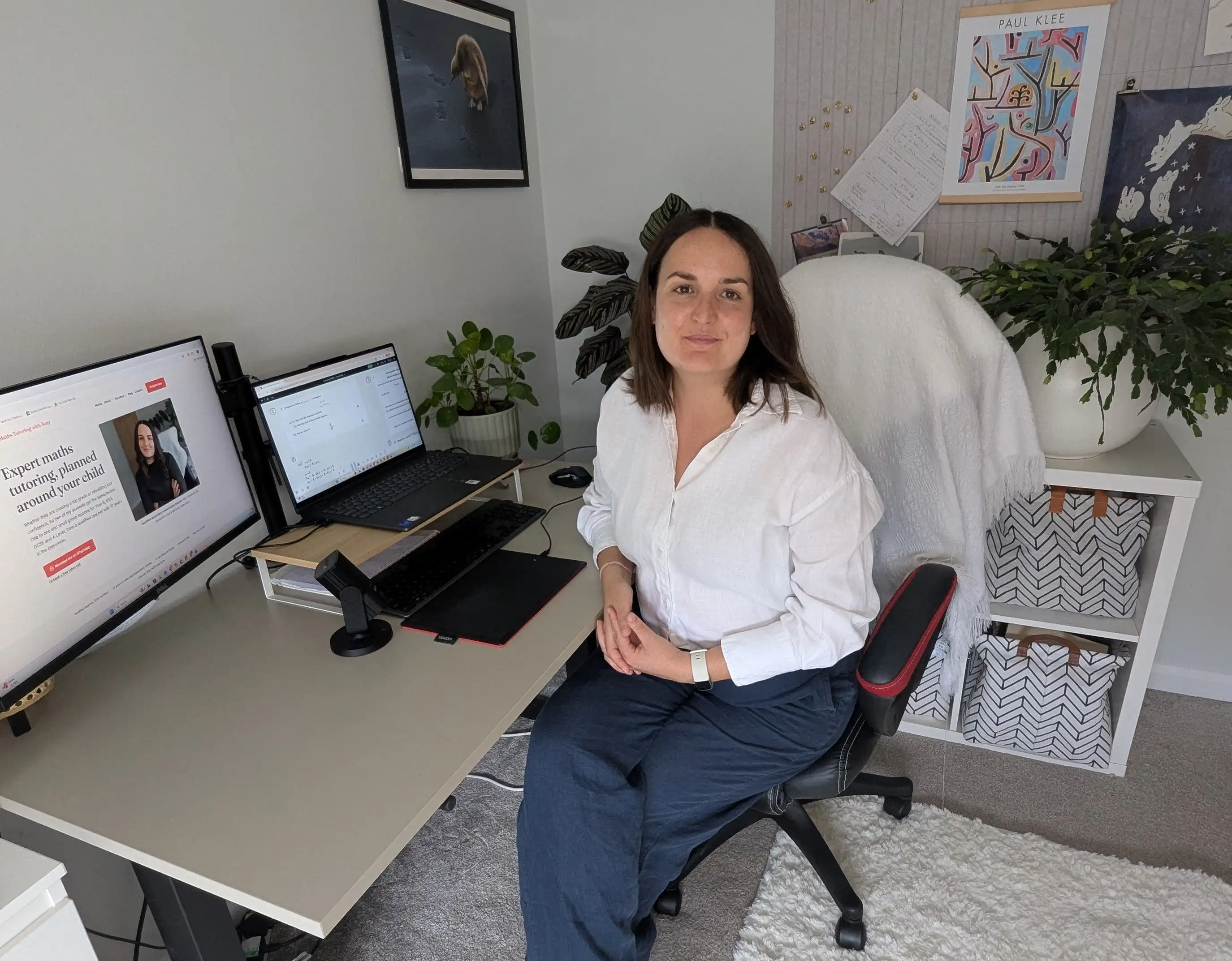 Amy at her home desk, with a maths problem open on the laptop and her graphics tablet beside the keyboard